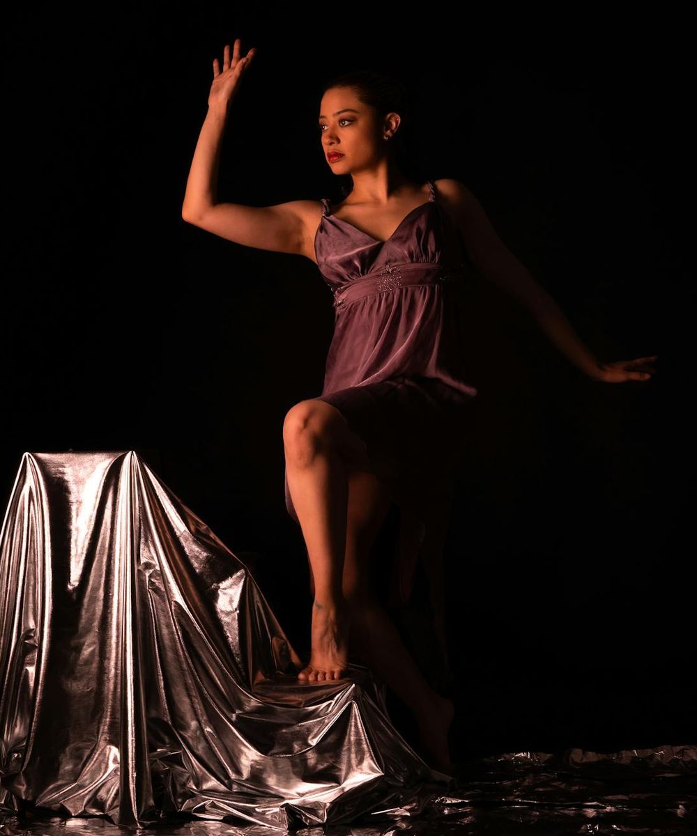 Active woman performing a rhythmic movement sequence in a dark studio.